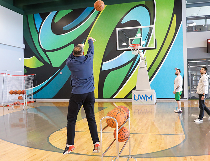 Happy team member throwing a basketball in the UWM gym