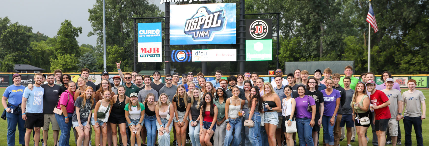 Landing page banner depicting a large group of UWM summer team members gathered in a large field